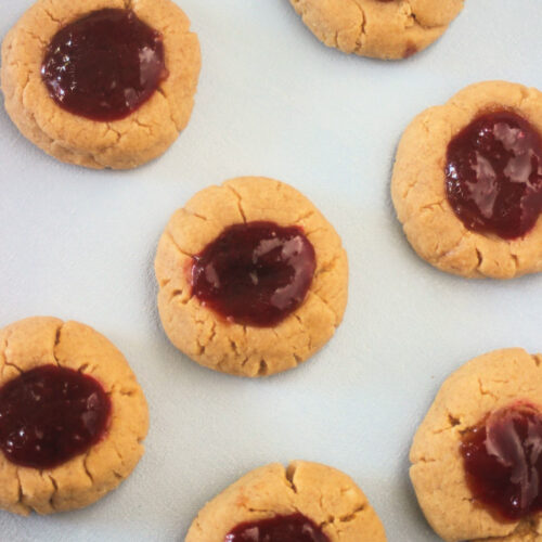 Top view of peanut butter thumbprint cookies on a white surface.
