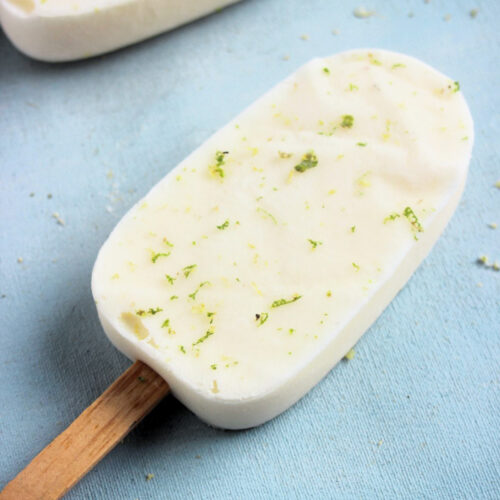 Lime popsicle on a light-blue surface.
