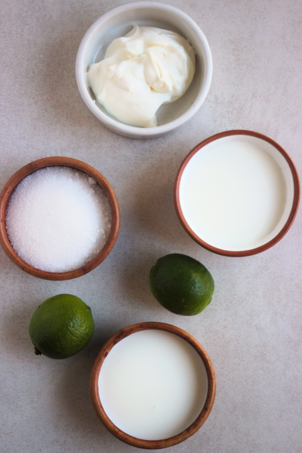 Top view of the main ingredients for lime popsicles on a white surface.