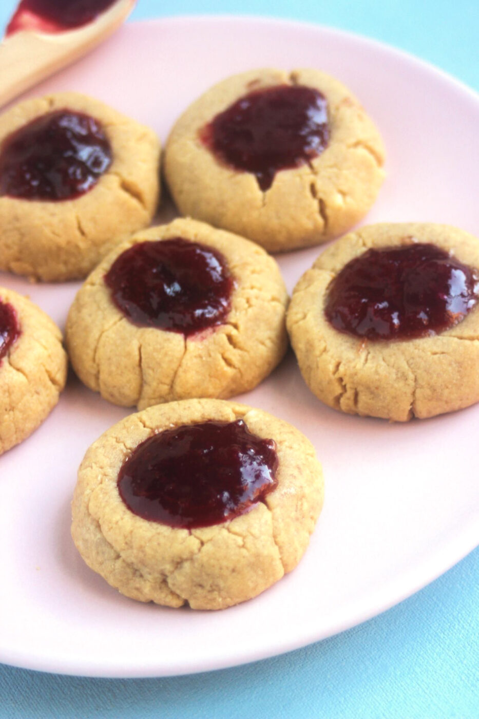 Peanut butter thumbprint cookies on a pink plate.
