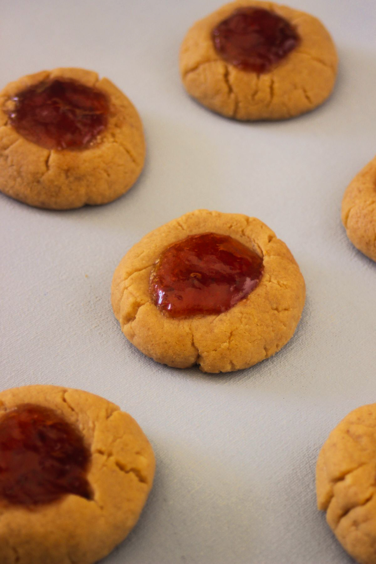 Peanut butter thumbprint cookies on a white surface.