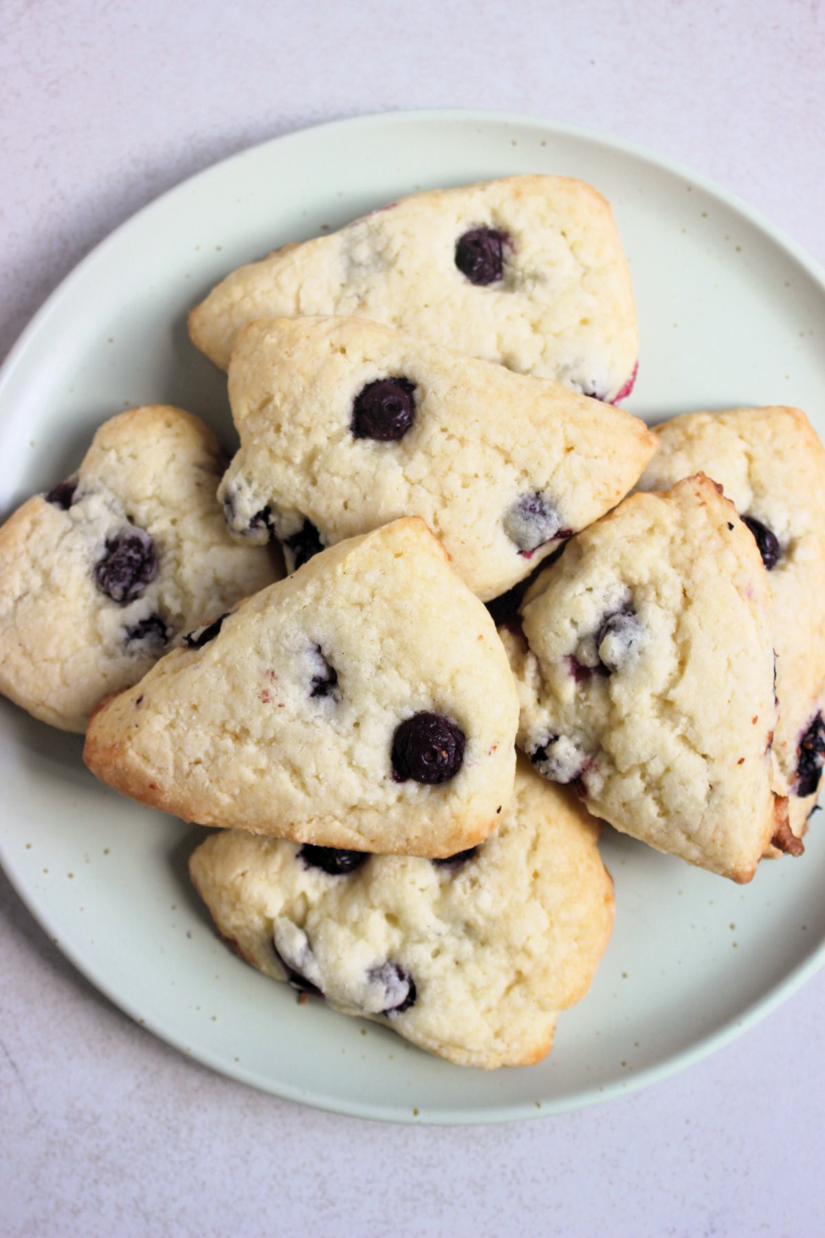 Blueberry scones on an aqua-green plate seen from above.