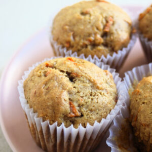 Carrot cake muffins in liners on a pink plate.