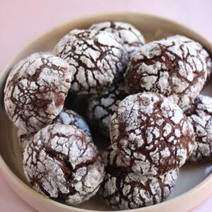 Many chocolate crinkle cookies on a plate.