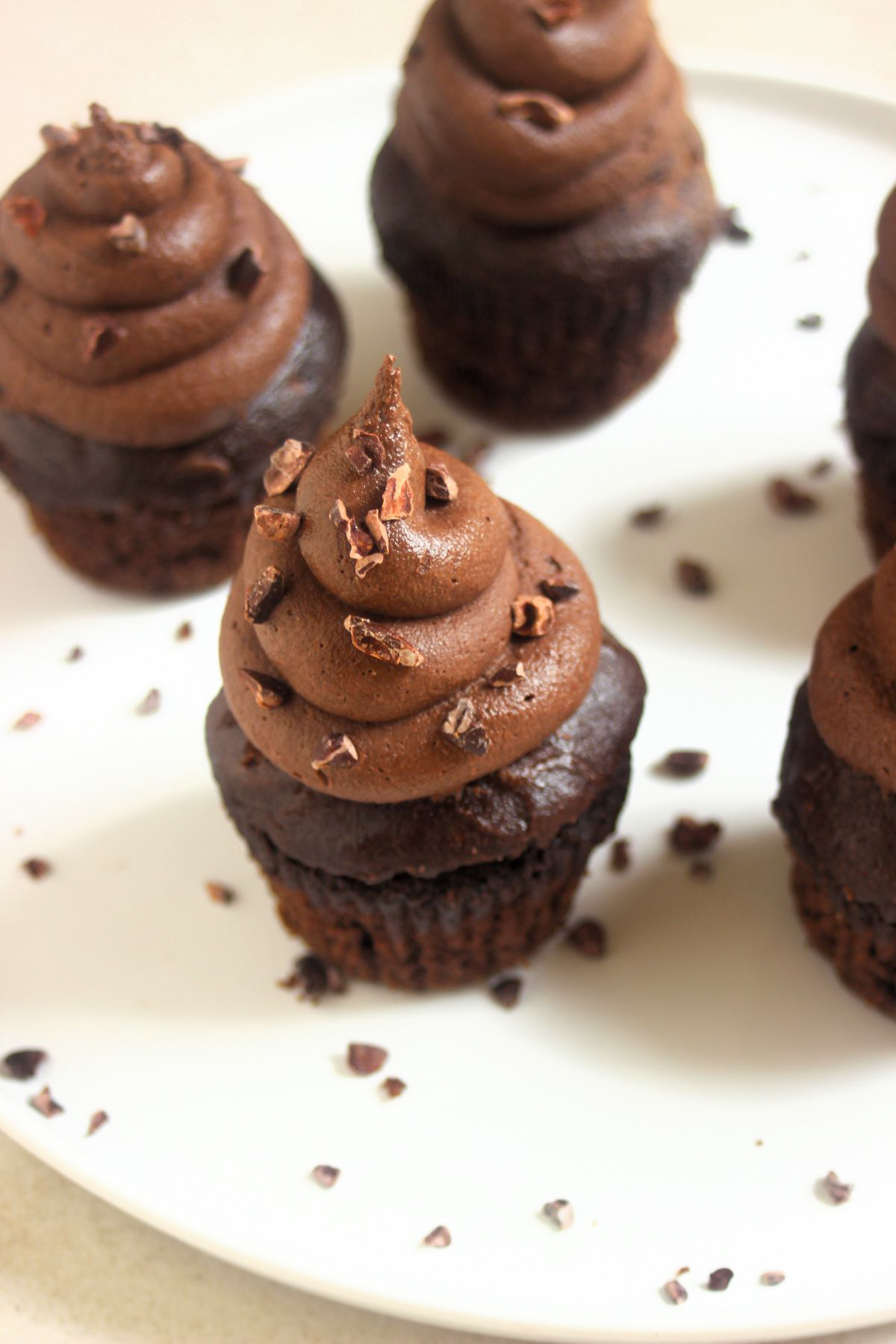 Chocolate cupacakes with cocoa nibs on a white plate.