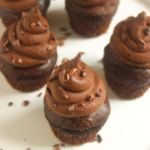 Chocolate cupacakes with cocoa nibs on a white plate.