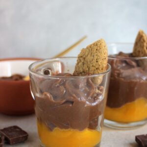 Glass cups with mango compote, chocolate mousse, and a piece of cookie.