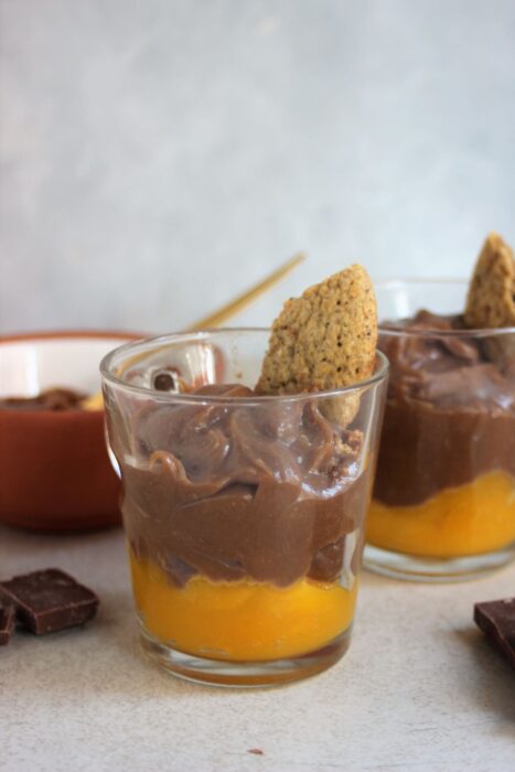 Glass cups with mango compote, chocolate mousse, and a piece of cookie.