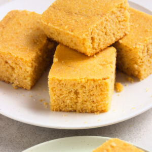 Many cornbread pieces on a white plate.
