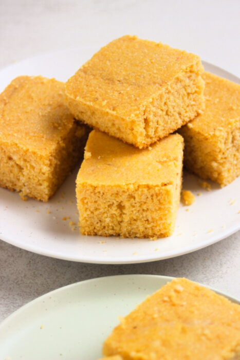 Many cornbread pieces on a white plate.