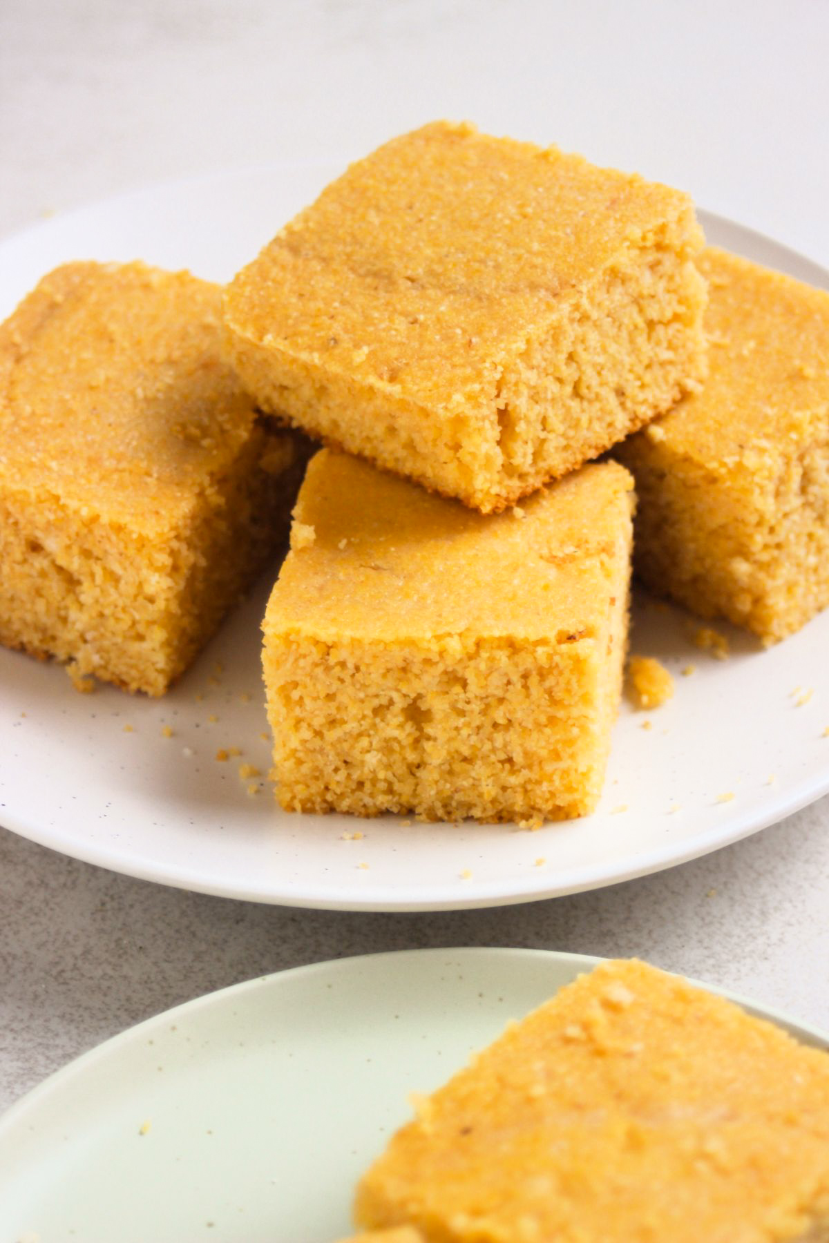 Many cornbread pieces on a white plate.