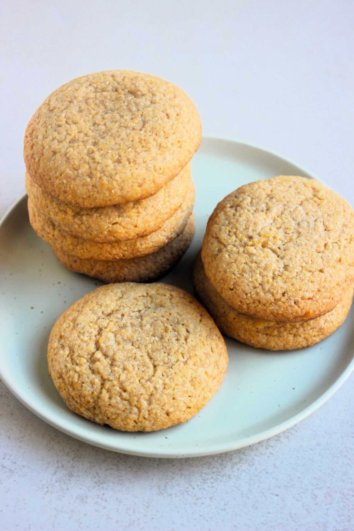 Cornmeal cookies stacks on an aqua-green plate.