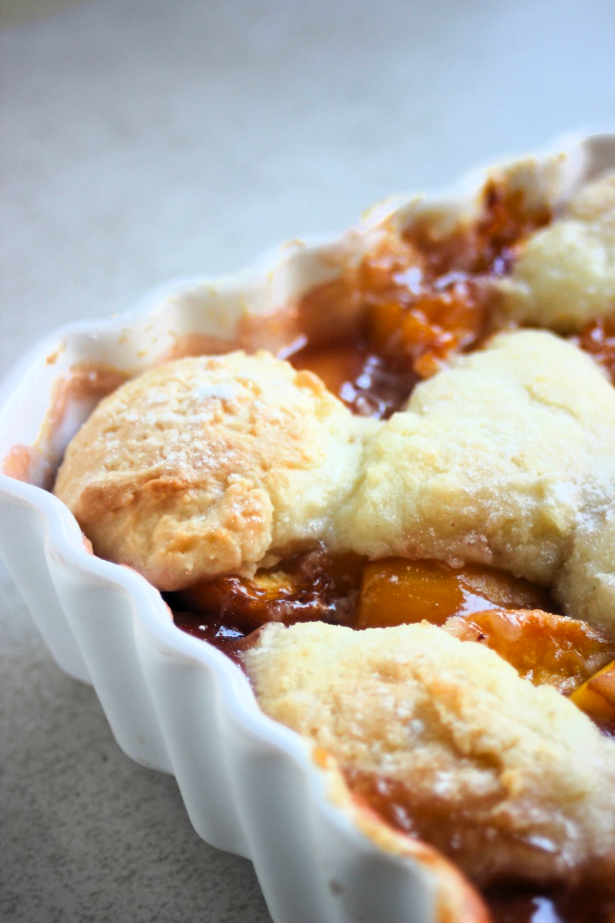 Partial close view of a baking dish with peach cobbler.