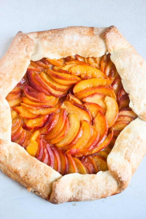 Peach galette on a white surface seen from above.