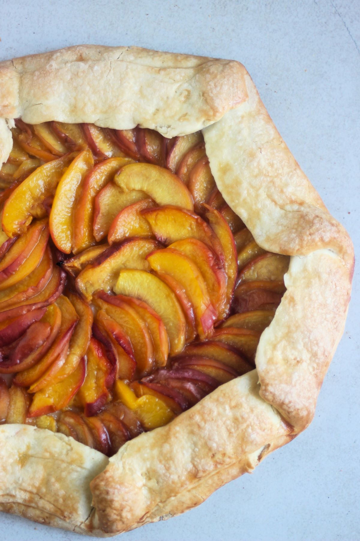 Seen of half peach galette on a white surface seen from above.