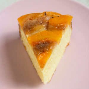 A portion of peach upside down cake on a pink plate.