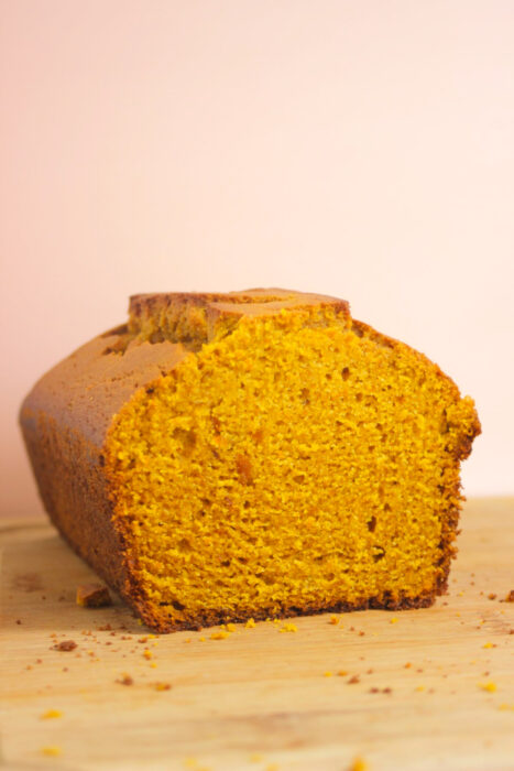 Pumpkin bread on a wooden table. Light pink background.