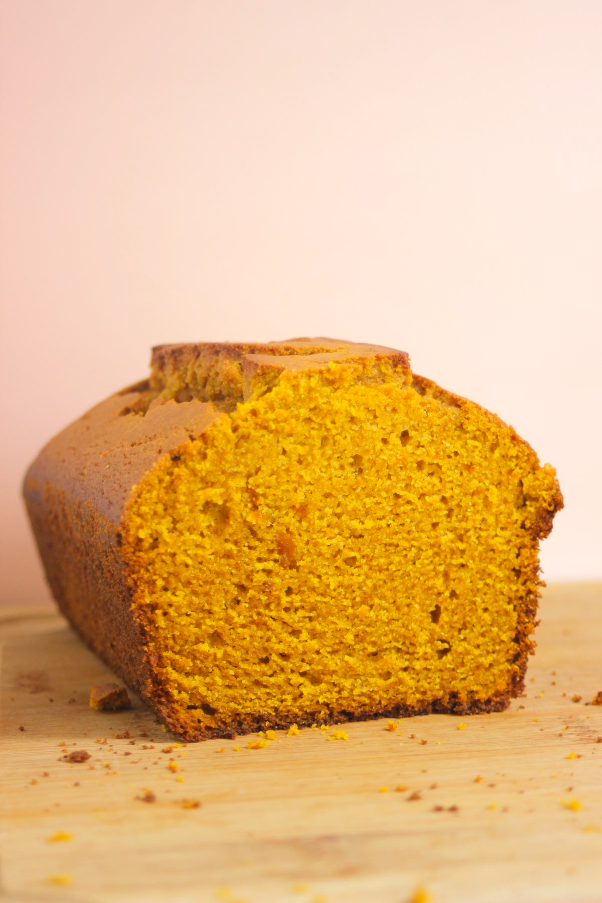 Pumpkin bread on a wooden table. Light pink background.