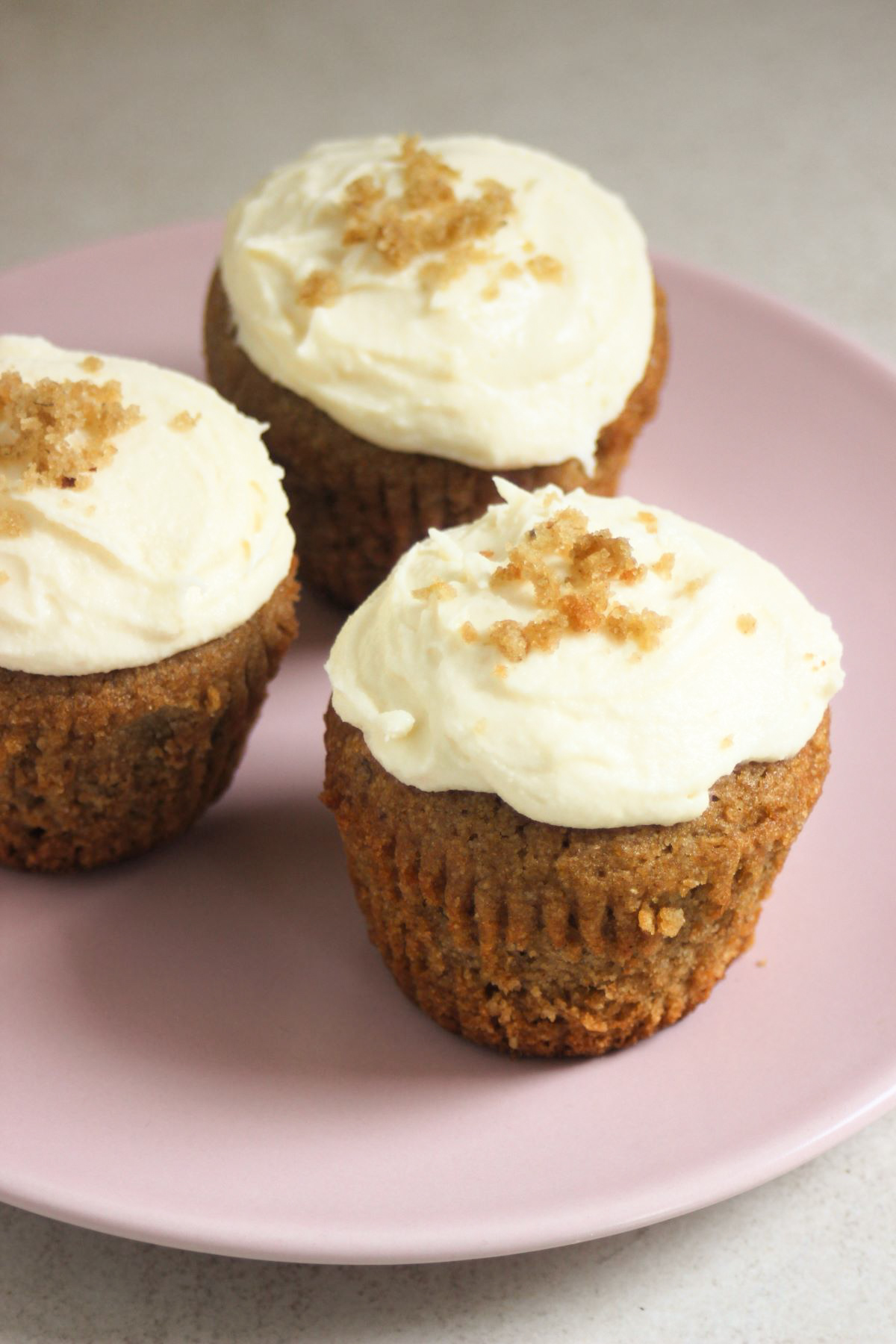 Sweet potato muffins with cream cheese frosting on a pink plate.