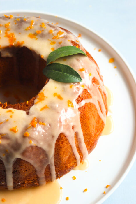 Gluten-free tangerine bundt cake, iced, on a white plate.