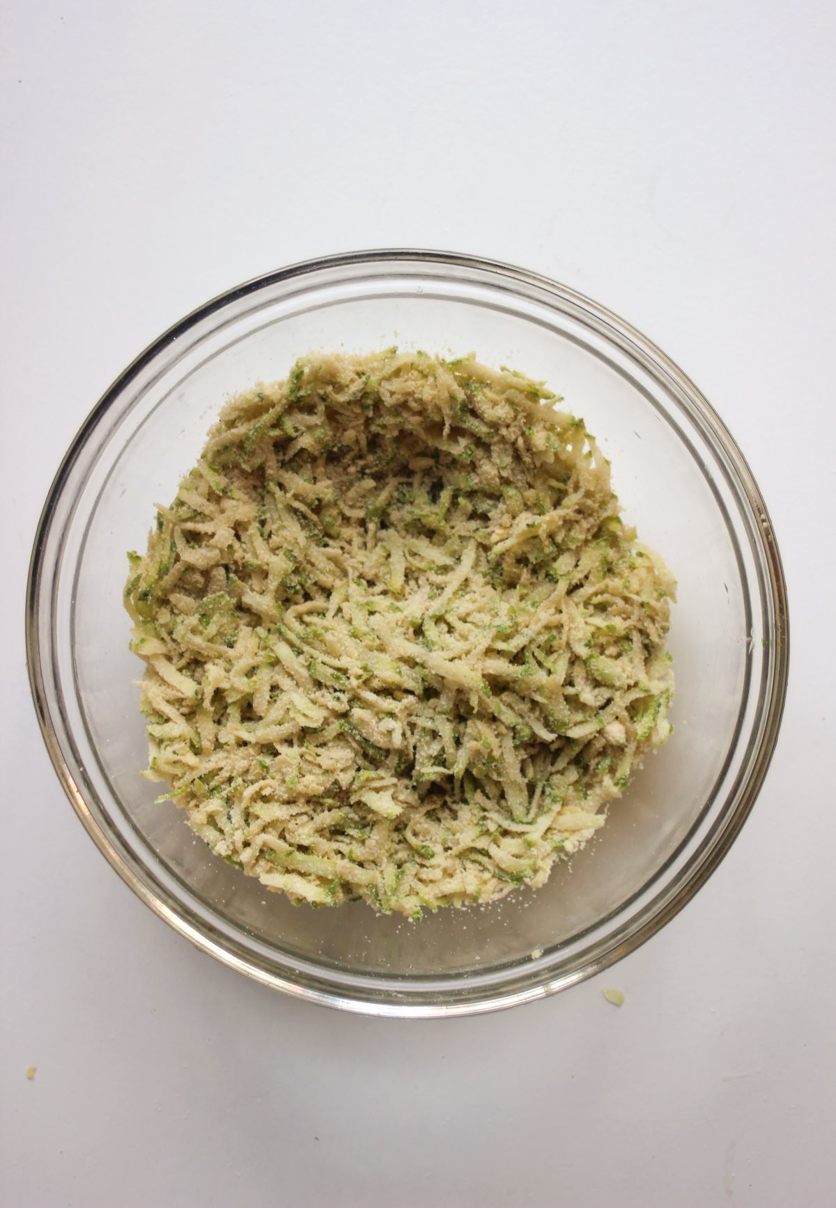 Glass bowl with a mixture that includes grated zucchini.