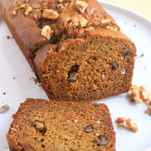Sweet potato bread with walnuts and two slices of it on a white plate.