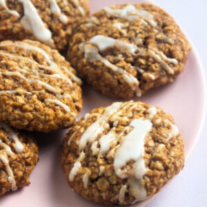 Pumpkin oatmeal cookies iced on a pink plate.