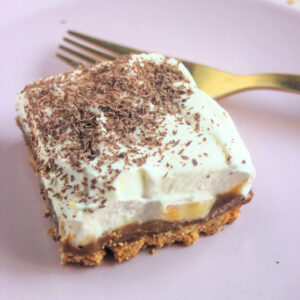 Banoffee pie bar on a pink plate and a golden fork.