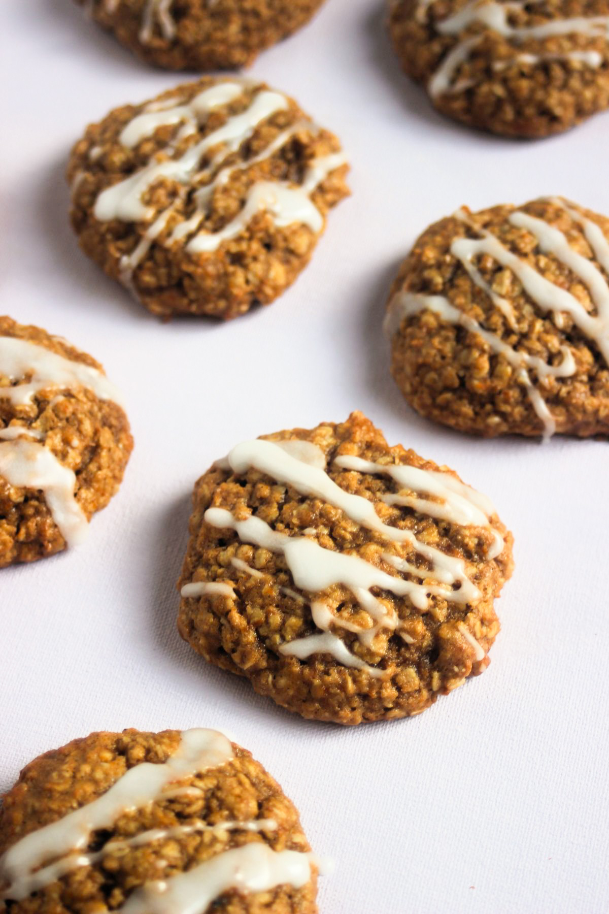 Pumpkin oatmeal cookies iced on white surface.
