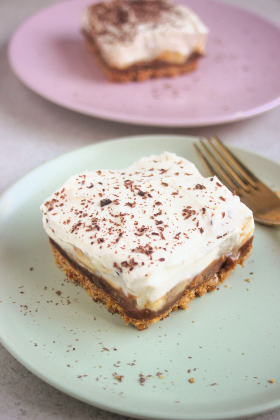 Banoffee pie bar on an aqua-green plate and a golden fork.