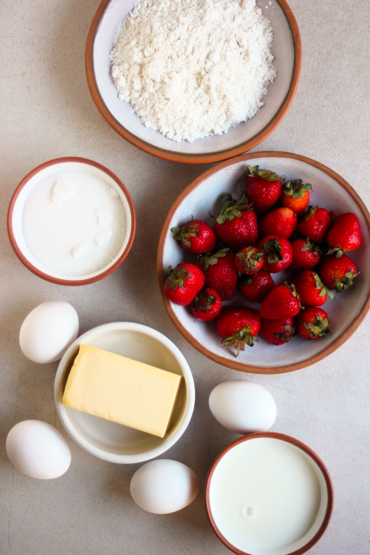 Top view of strawberry jelly tart ingredients on a white surface.