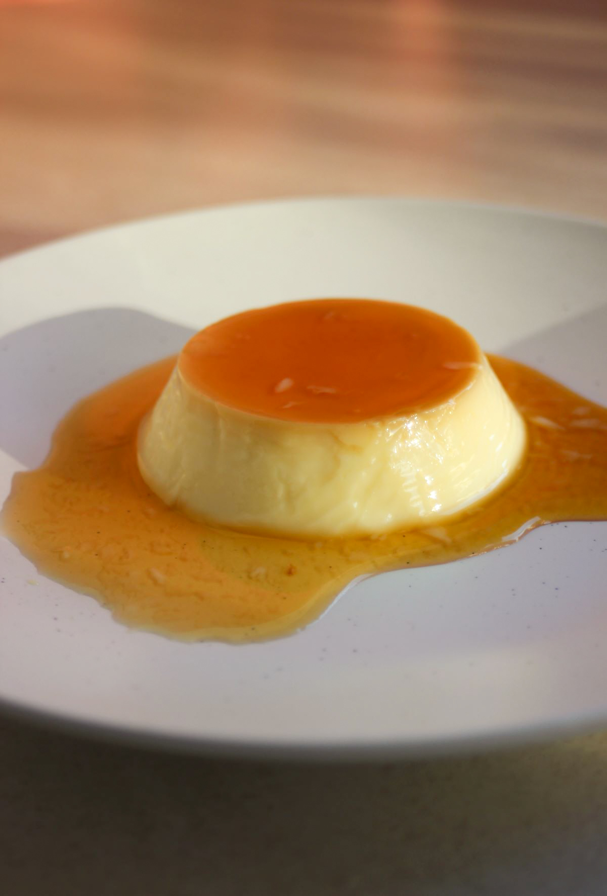 Individual flan with caramel on a white plate.