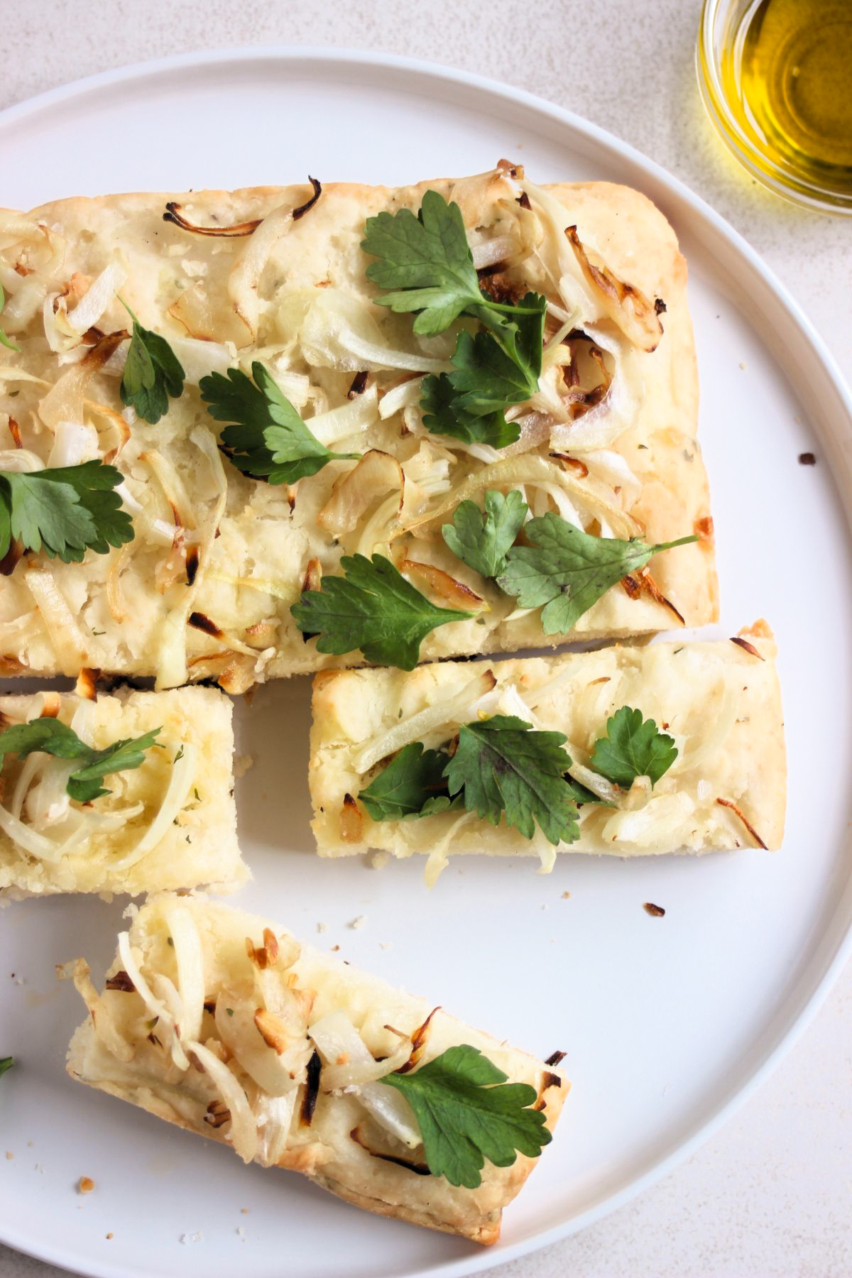 Top view of onion focaccia sliced on a white plate.