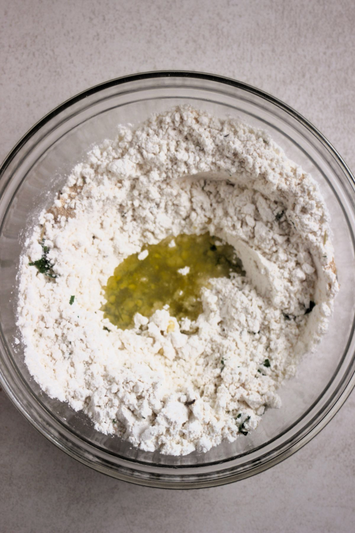 Glass bowl with focaccia dry ingredients and oil in the center.