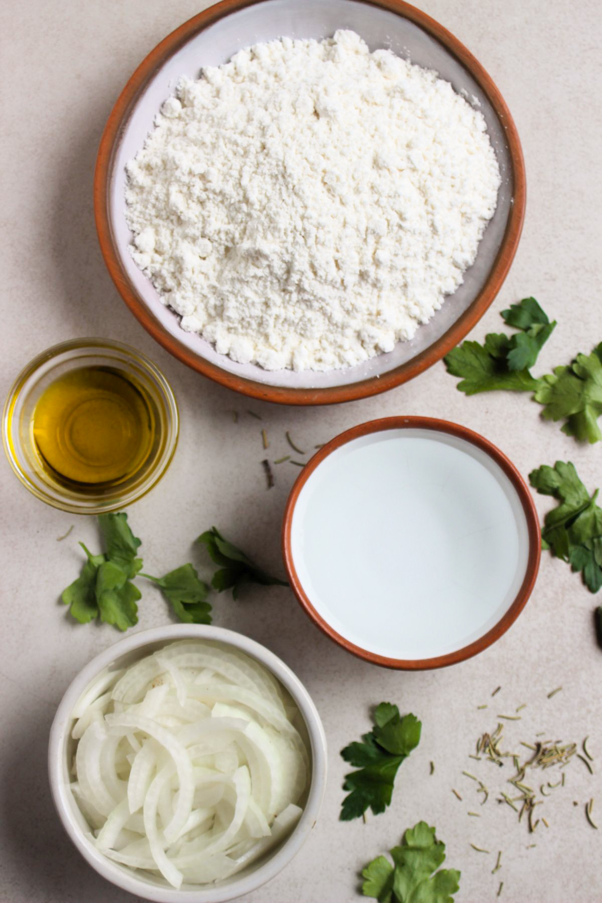 Top view of onion focaccia ingredients on a white surface.