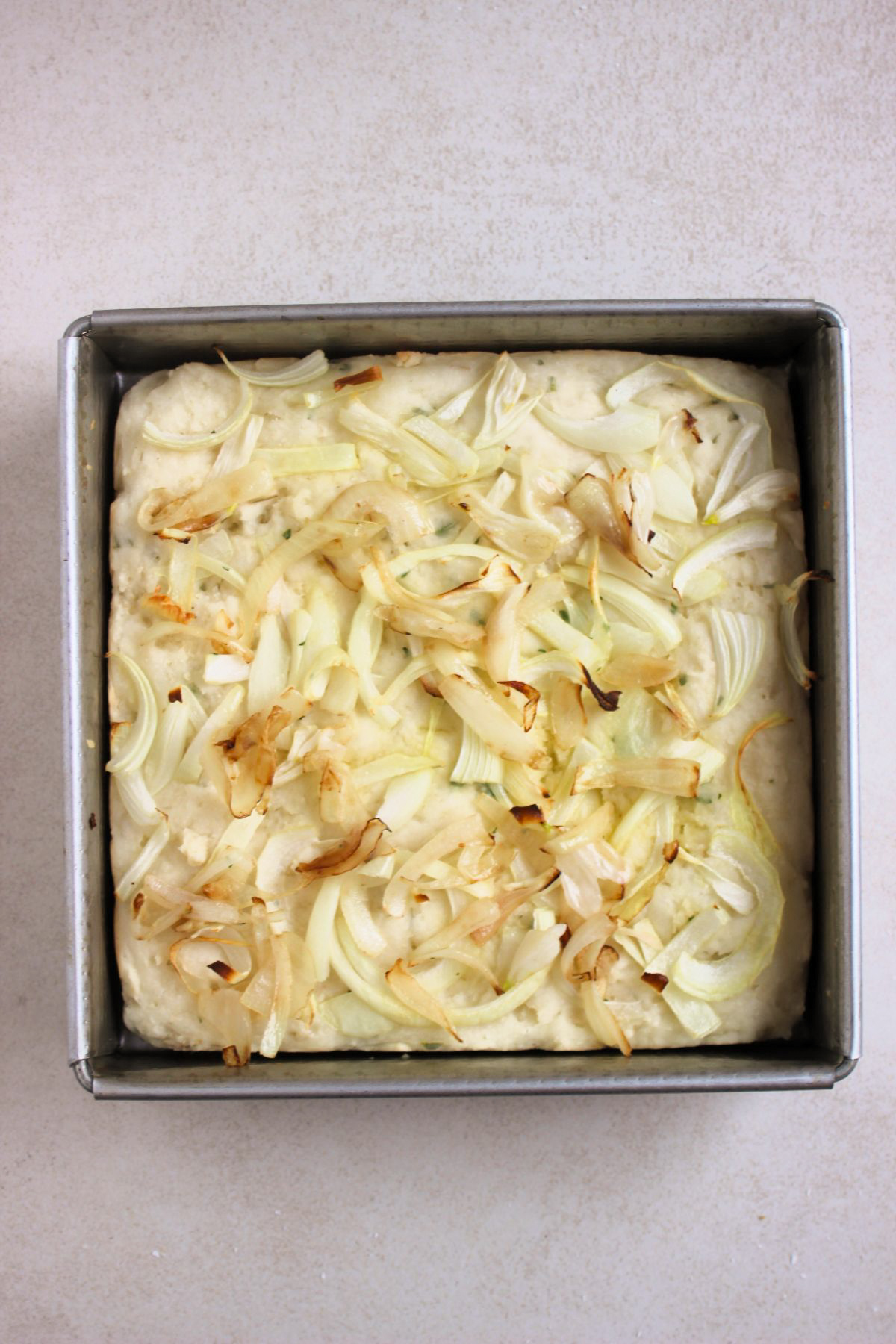 Square baking pan with focaccia and onion slices after baking.