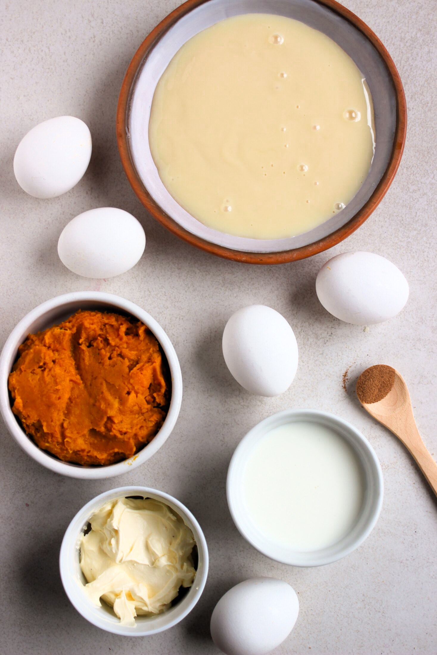 Top view of pumpkin flan ingredients on a white surface.