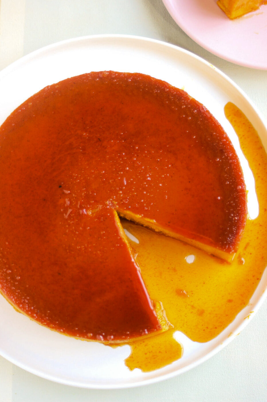 Top view of pumpkin flan with caramel, without one portion, on a white plate.
